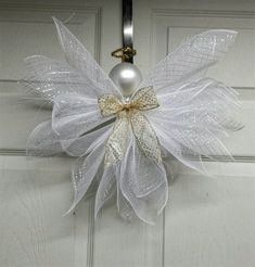 a door hanger decorated with white mesh and a gold bow hanging on the front door