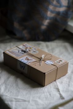 a brown box sitting on top of a bed covered in white sheets and paper with stickers