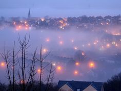 a foggy night with street lights and houses in the distance