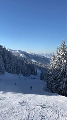 skiers are skiing down a snowy slope in the mountains