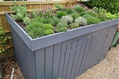 an outdoor garden with various plants growing in the planter box, along side a wooden fence