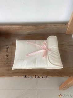 a wooden bench with a white blanket on it and a pink ribbon tied around the edge