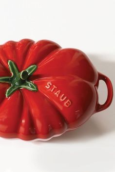 a red ceramic tomato shaped dish with the word stup on it's side