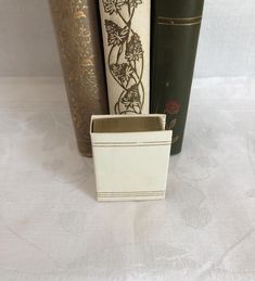 three books are stacked next to each other on a white tablecloth with gold trimmings