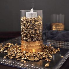 a candle that is sitting in some kind of glass with gold flakes around it