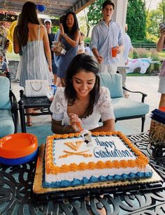 a woman sitting at a table with a cake in front of her and people standing around