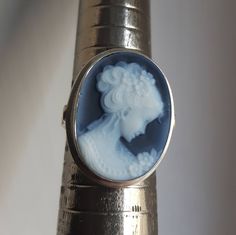 "Blue agate stone cameo ring featuring young lady profile with torchon hair set in 925 sterling silver. Cameo size: 1,8cm Ring size: adjustable Contact me for any other request | Customized works also available. Our cameo tecnique respects the ancient cameo tradition consisting in a shell, gemstone, coral, mother of pearl carved with a design in low relief in which the raised design and the background consist of layers of contrasting colours. Every item is really unique because it is carved by h Elegant Cameo Rings, Formal Silver Cameo Rings, Elegant Silver Cameo Rings, Blue Agate Stone, Hair Set, Cameo Earrings, Cameo Jewelry, Cameo Ring, Hair Setting