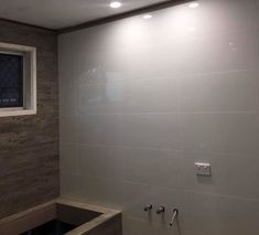 an empty bathroom with white tile and wood accenting the walls, along with no shower curtain