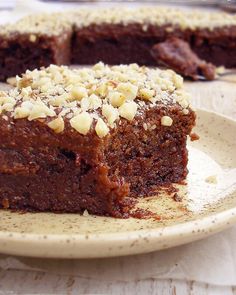 a piece of chocolate cake on a plate with some nuts in the middle and one slice missing