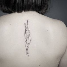 the back of a woman's neck with a flower tattoo on it