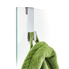 a green towel hanging on the side of a glass door with a hook in it