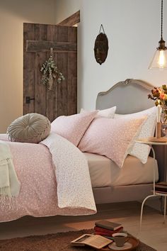 a bed with pink and white comforters in a bedroom next to a wooden door