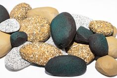 there are many different colored rocks on this white surface, including one with black and gold sprinkles