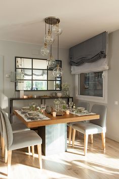 the dining room table is set with place settings for four people and has glass globes hanging from the ceiling