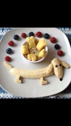 a white plate topped with fruit and a dog cut out in the shape of a banana