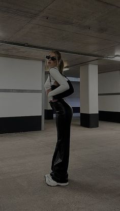 a woman is standing in an empty parking garage with her hands on her hips and looking off into the distance