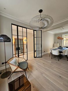 a dining room and living room with wood floors, white chairs and glass partitions