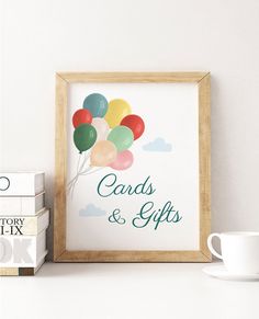 some books and a cup on a white shelf with a framed poster that says cards & gifts