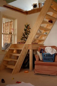 a living room filled with furniture and a wooden stair case next to a christmas tree