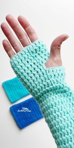 a hand wearing a blue knitted mitt next to a pair of wrist warmers