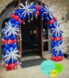 an arch decorated with red, white and blue balloons