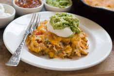 a white plate topped with lasagna covered in cheese and guacamole