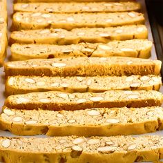 several slices of bread are lined up on a baking sheet with almonds all over them