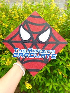 someone is holding up a spiderman graduation cap