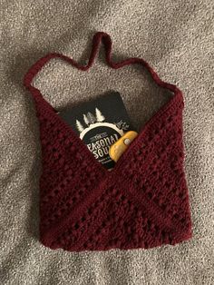 a red crocheted bag with a book in the pocket on top of it