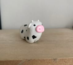 a cow figurine sitting on top of a wooden table next to a wall