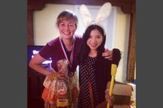 two women standing next to each other with bunny ears on their heads and holding brooms