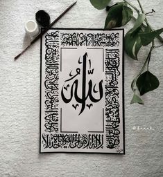 an arabic calligraphy is displayed on a white surface with some scissors and other items