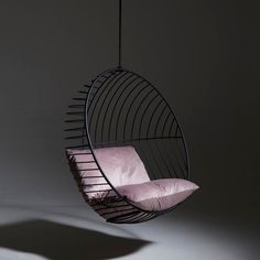 a hanging chair with pink pillows in the dark