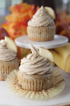 three cupcakes with frosting and apples on top