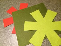 two pieces of paper cut out to look like an x on the floor with red and green squares