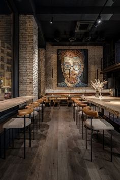 an empty restaurant with tables and stools in front of a large painting on the wall