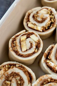 several cinnamon rolls in a baking pan with nuts on the top and one rolled up