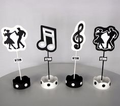 four black and white paper cutouts with music notes on them, sitting on a table