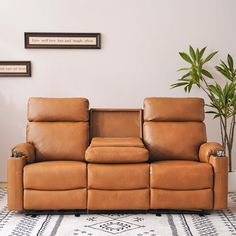 a brown leather reclining couch sitting on top of a rug next to a potted plant