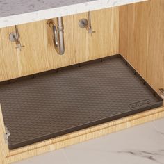 a kitchen counter with a brown mat on it and two faucets in the background