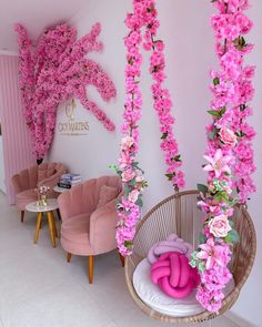 pink flowers are hanging from the ceiling in a room with chairs and tables on either side