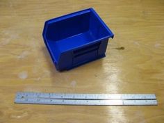 a blue container sitting on top of a wooden table next to a ruler