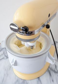 an electric mixer sitting on top of a white and yellow countertop next to a black cord