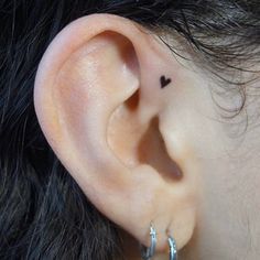 a close up of a person's ear with a small heart tattoo on it