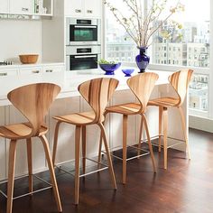 four chairs are lined up in front of an island with white countertops and cabinets