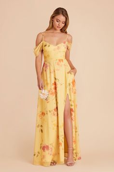 a woman wearing a yellow floral print dress with thigh high slits and open shoulders