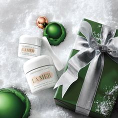 a green gift box with two creams in it and a christmas ornament next to it