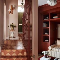 an entry way leading to a living room and dining room with red bookcases