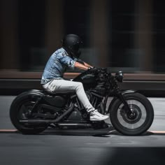 a man riding on the back of a motorcycle down a street in front of a building