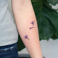 a woman's arm with three small flowers on the left side of her arm